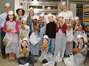 Gruppenbild der Kinder mit Prof. Müssig, Vollkornbäcker Georg Kretzschmar und Dr. Ursula Hofer in weißen Bäckermützen stolz die Brote zeigend.