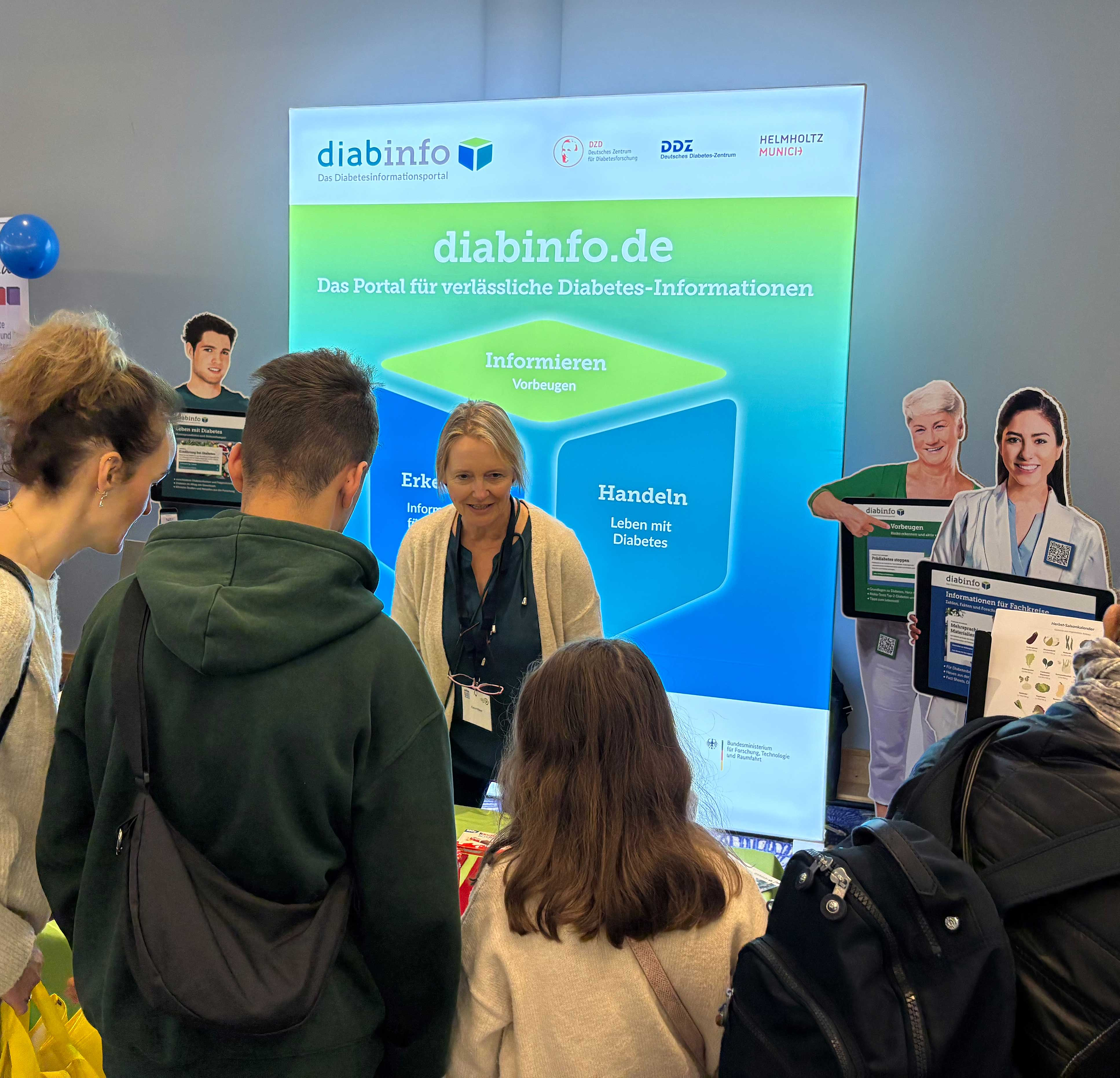 Messestand mit Banner von diabinfo.de und mehreren Personen, die sich informieren