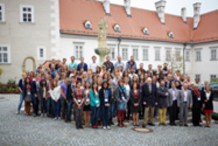 Gruppenbild mit rund 95 Personen auf den STufen vor einem Brunnen im historischen Burghof im Stift Klosterneuburg