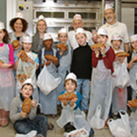 Gruppenbild der Kinder mit Prof. Müssig, Vollkornbäcker Georg Kretzschmar und Dr. Ursula Hofer in weißen Bäckermützen stolz die Brote zeigend.