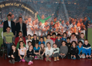 Gruppenbild der teilnehmenden Kinder vor einem Plakat der deutschen Fußball-Nationalmannschaft bei der Weltmeisterschaft 2014
